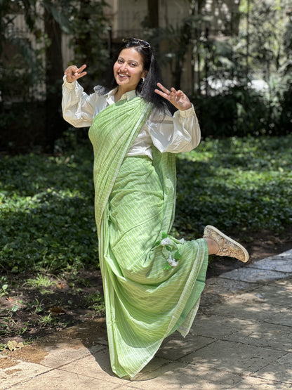Light green mul cotton saree with subtle white stripes.